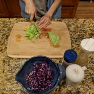Chopping up green and purple cabbage to prepare savory vinaigrette cole slaw.